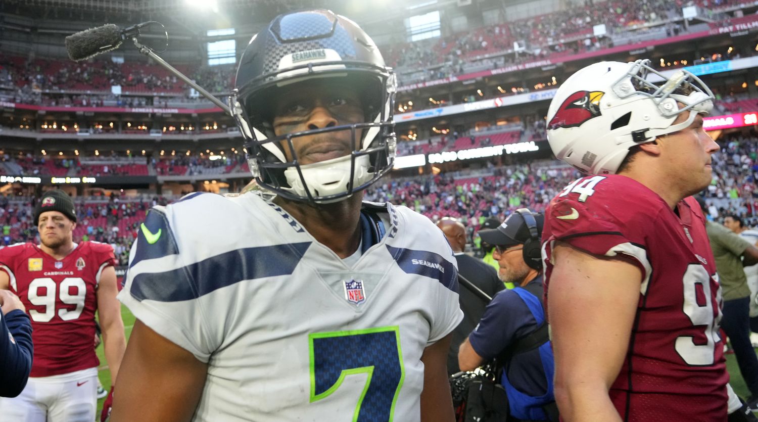 Seattle Seahawks quarterback Geno Smith wears a helmet surrounded by Cardinals players